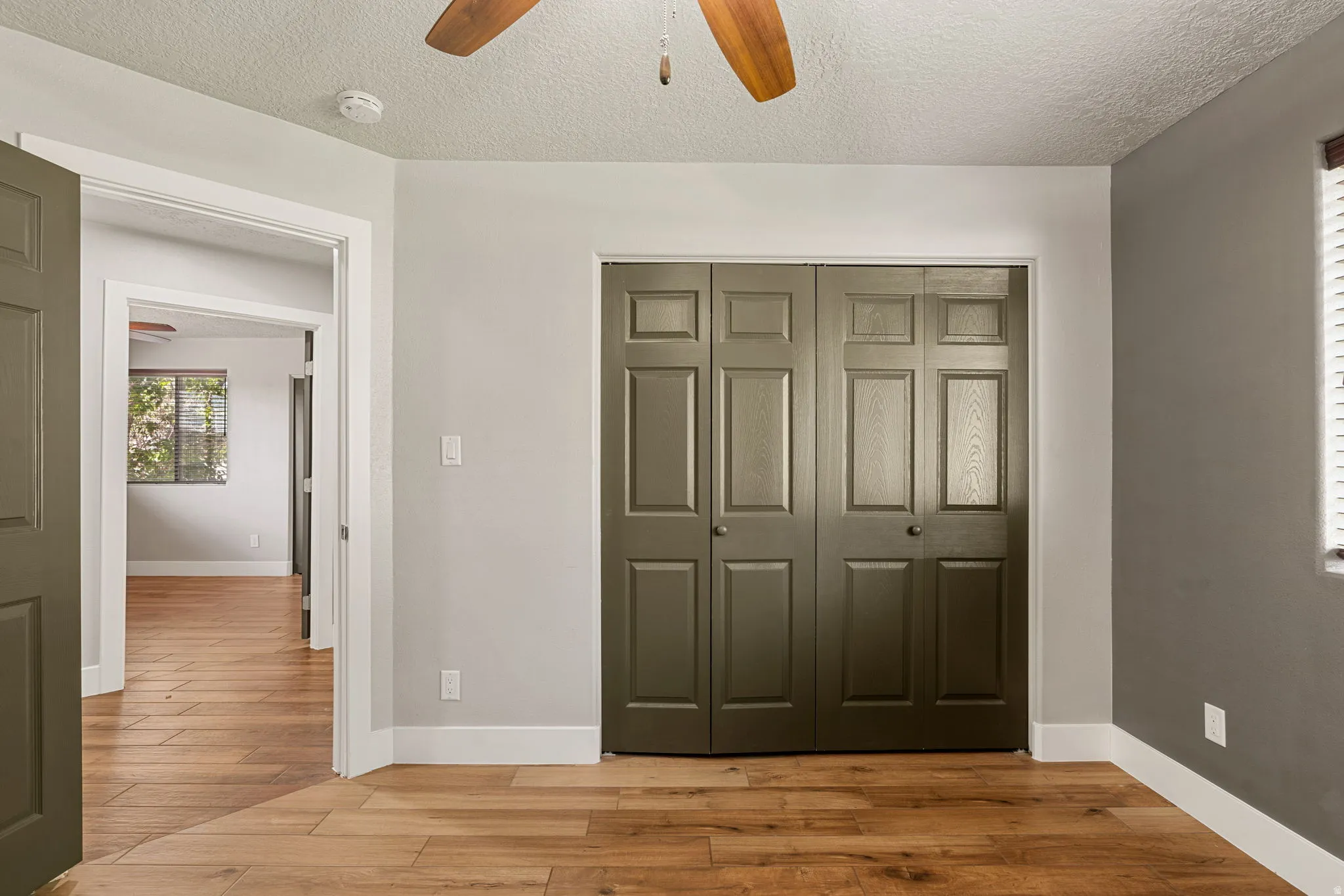Unfurnished bedroom with light wood finished floors, a textured ceiling, a closet, and ceiling fan