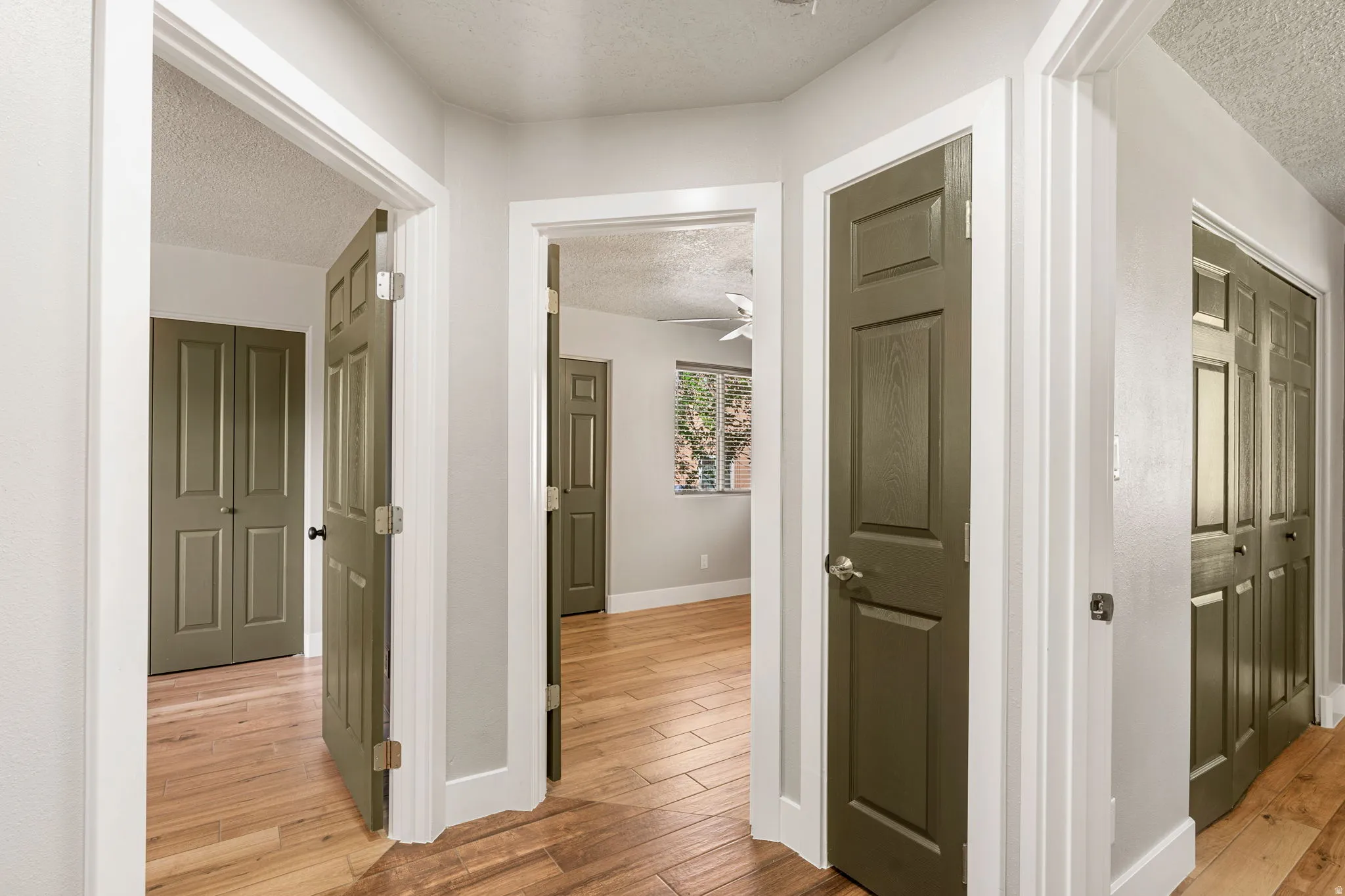 Corridor featuring a textured ceiling and light wood-style floors