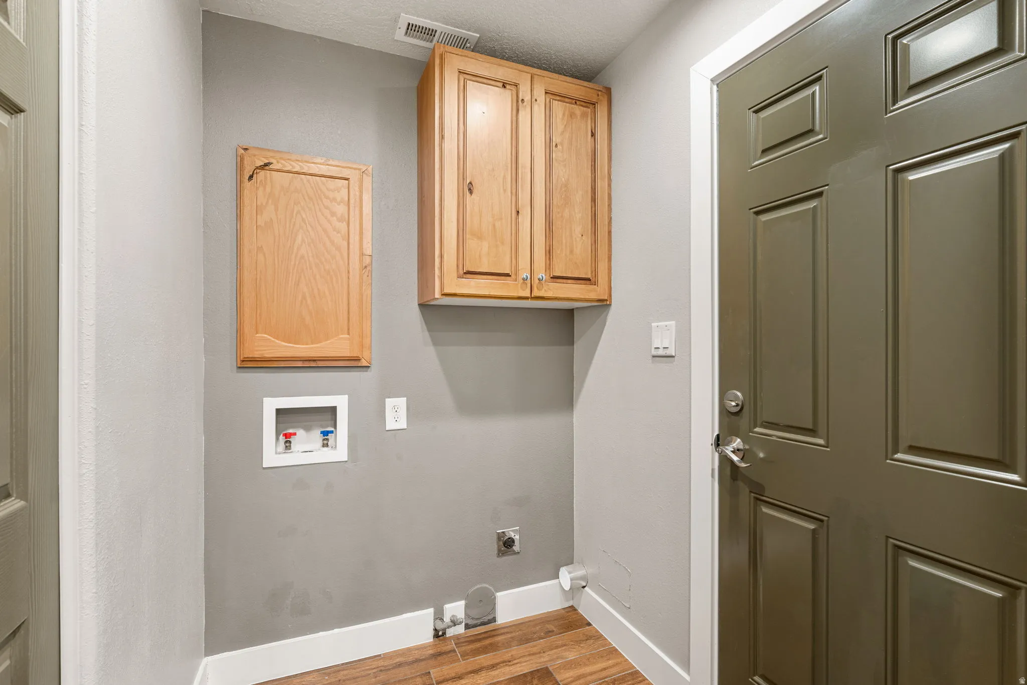 Laundry area featuring light wood-style flooring, electric dryer hookup, hookup for a washing machine, and cabinet space
