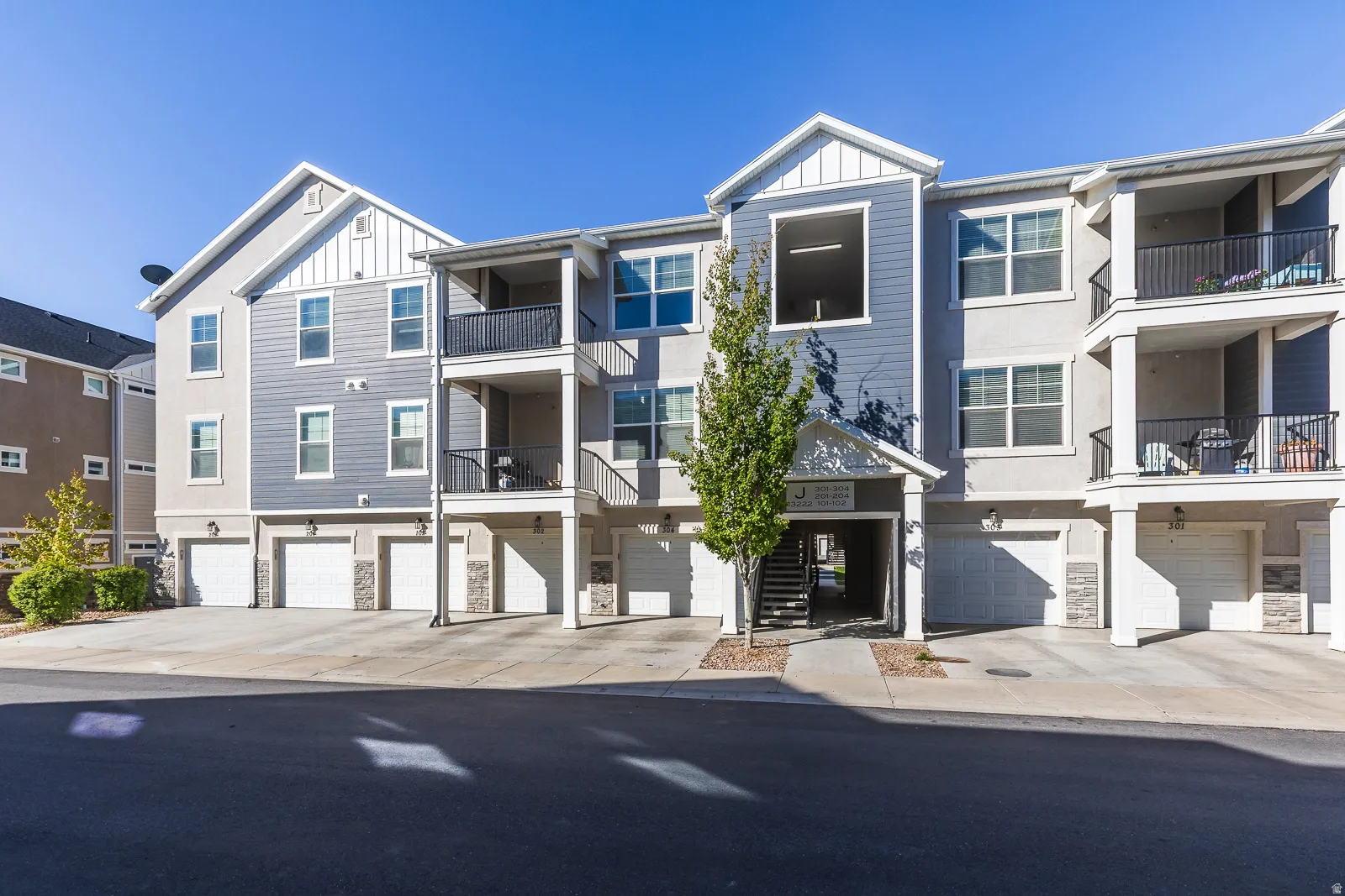 View of apartment building / complex featuring an attached garage and driveway