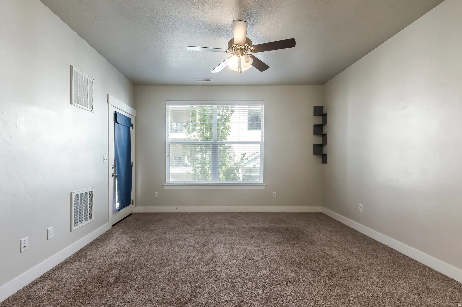 Carpeted spare room with a ceiling fan and a textured ceiling