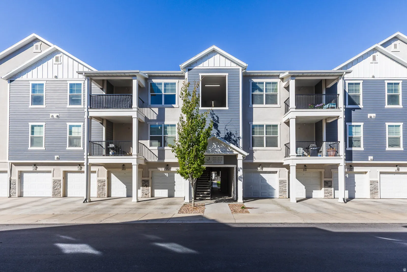 View of apartment building / complex featuring an attached garage and driveway