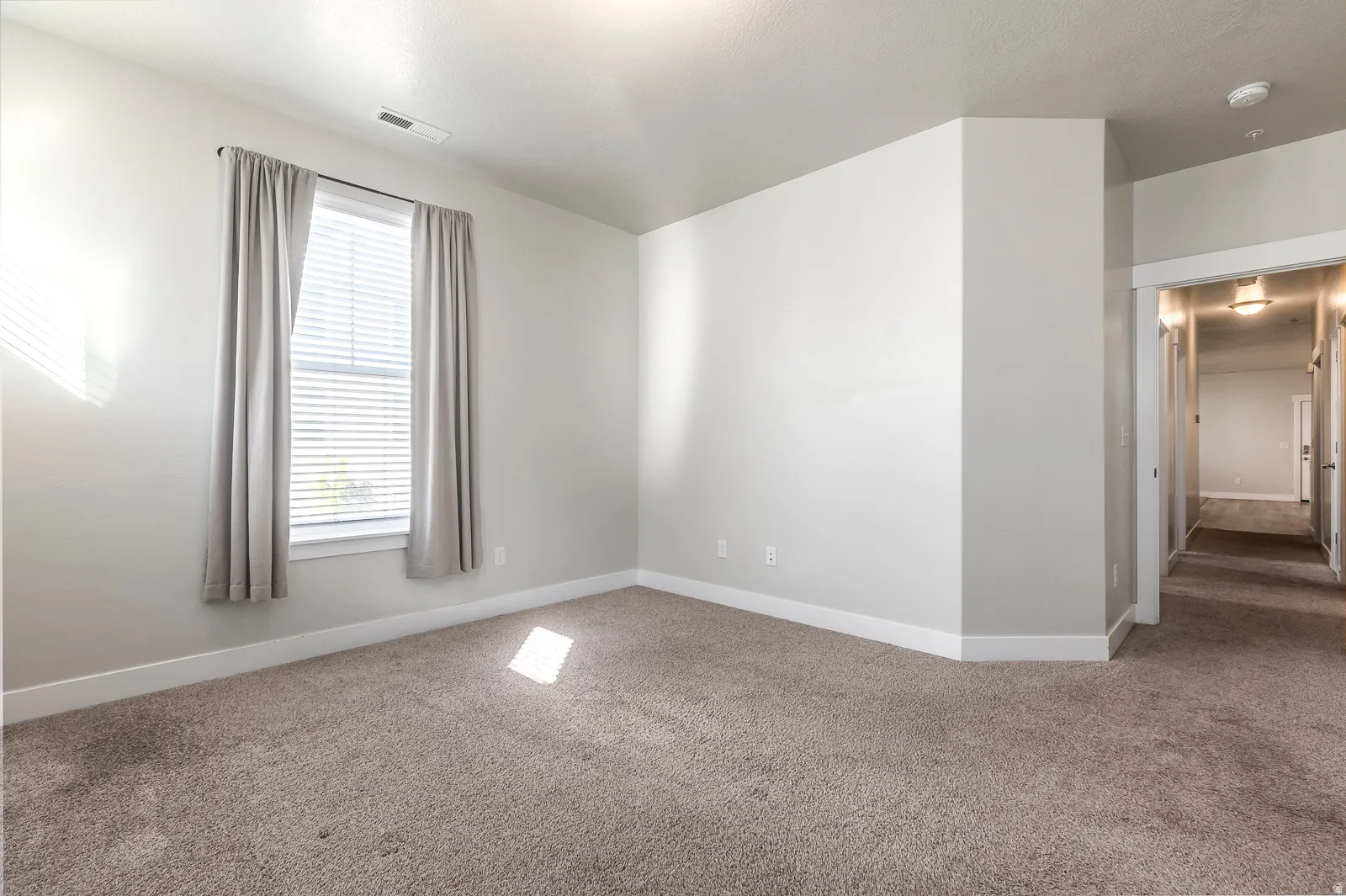 Carpeted spare room featuring baseboards and a smoke detector