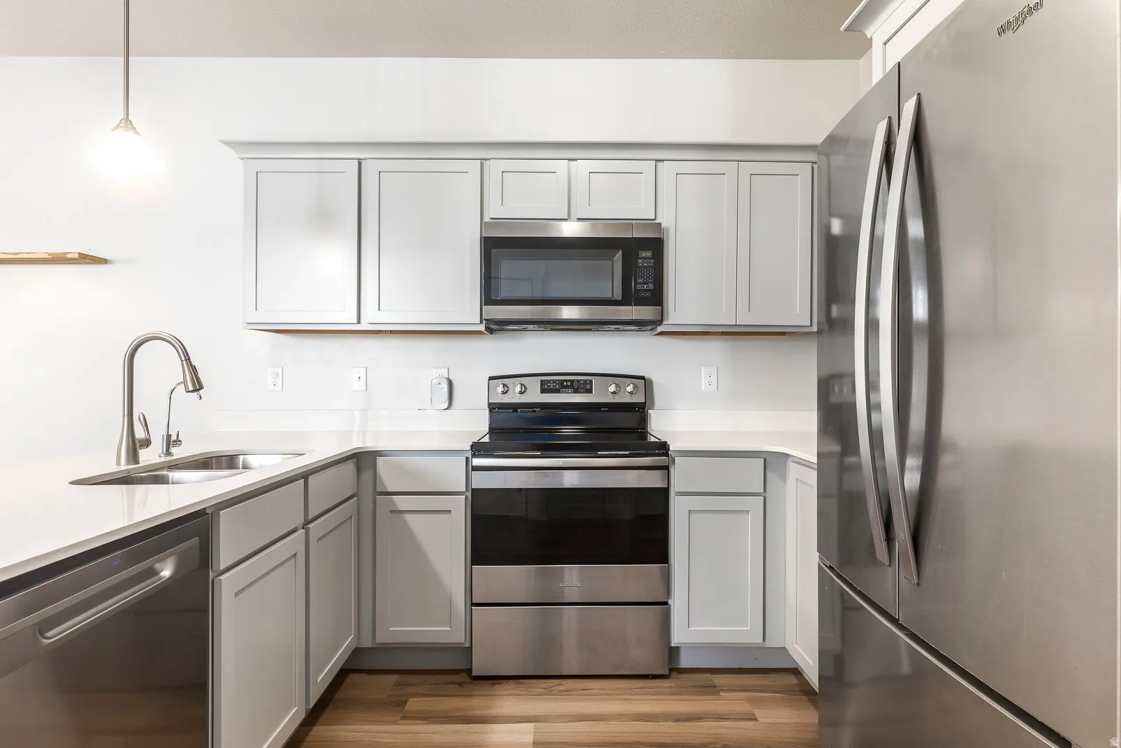 Kitchen with gray cabinetry, stainless steel appliances, pendant lighting, and dark wood finished floors