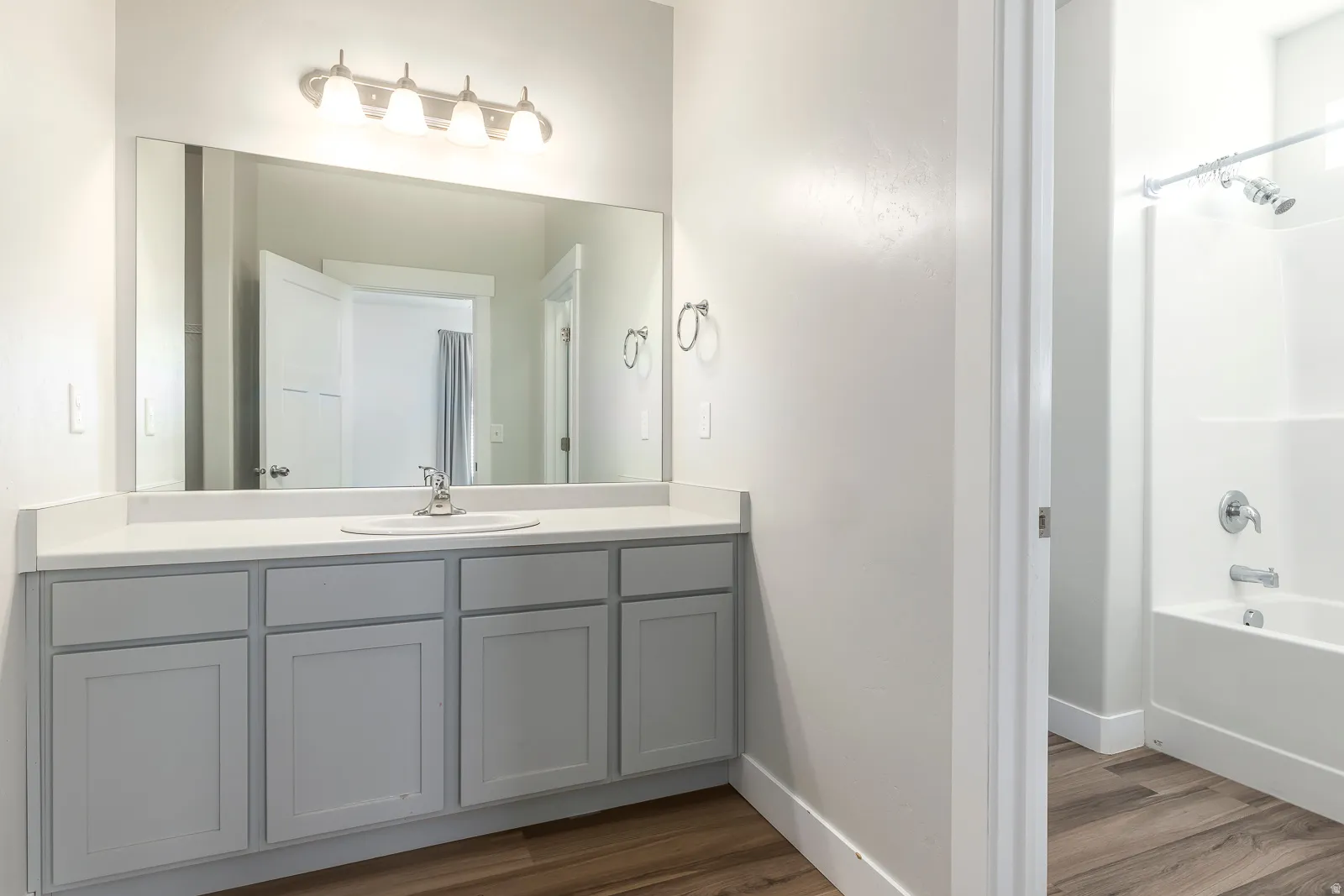 Bathroom featuring dark wood finished floors, vanity, and tub / shower combination