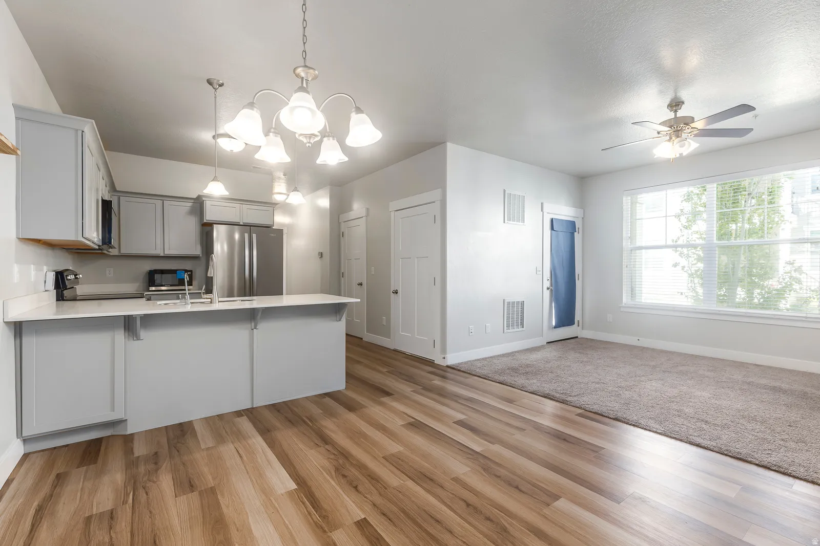 Kitchen with suspended lighting, a peninsula, gray cabinetry, a breakfast bar area, and stainless steel appliances