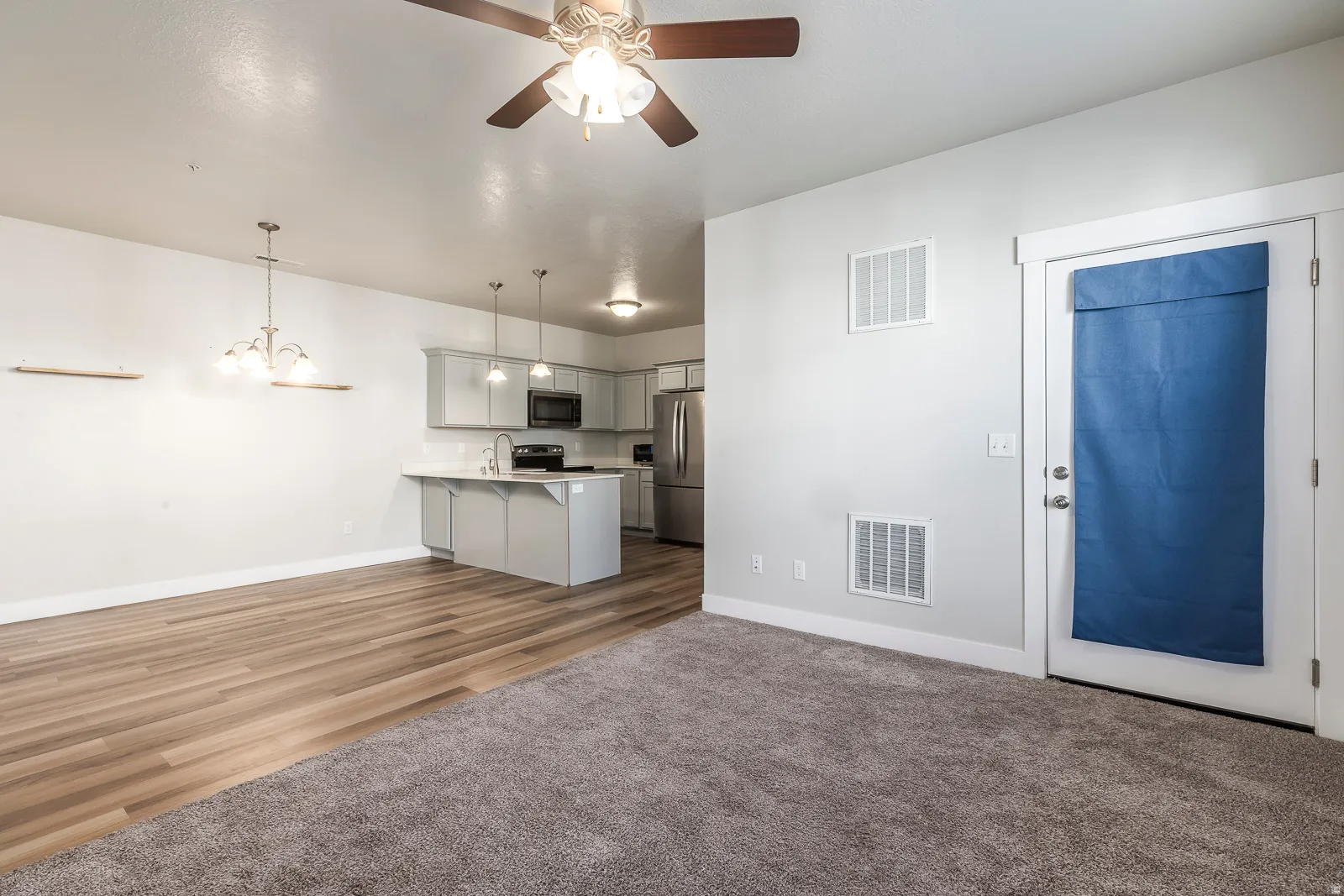 Kitchen with open floor plan, gray cabinets, a kitchen bar, ceiling fan, and stainless steel appliances