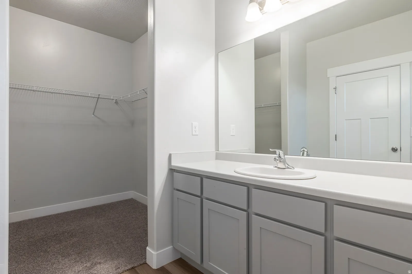 Bathroom with a spacious closet, vanity, a textured ceiling, and light carpet