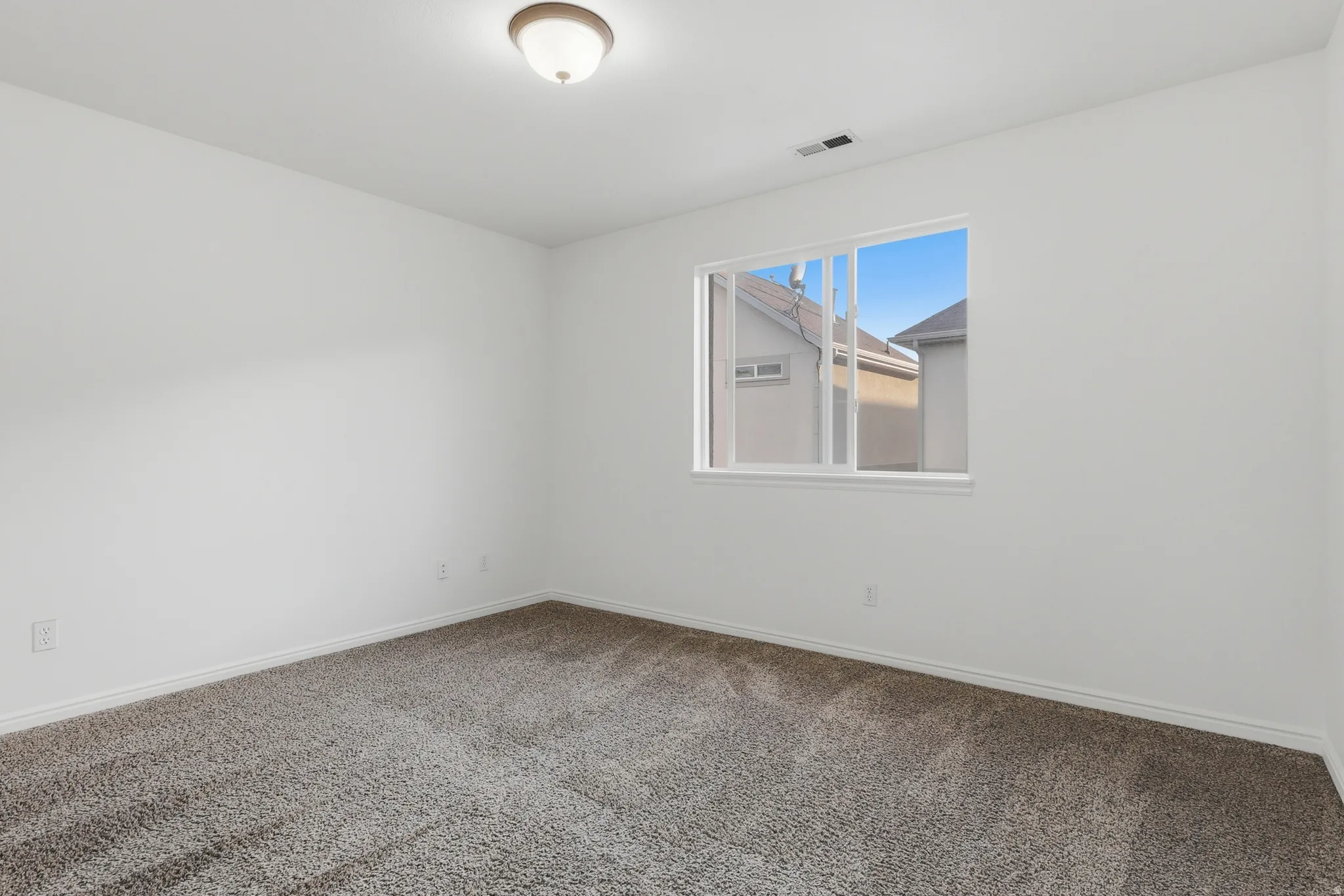 Carpeted spare room featuring baseboards