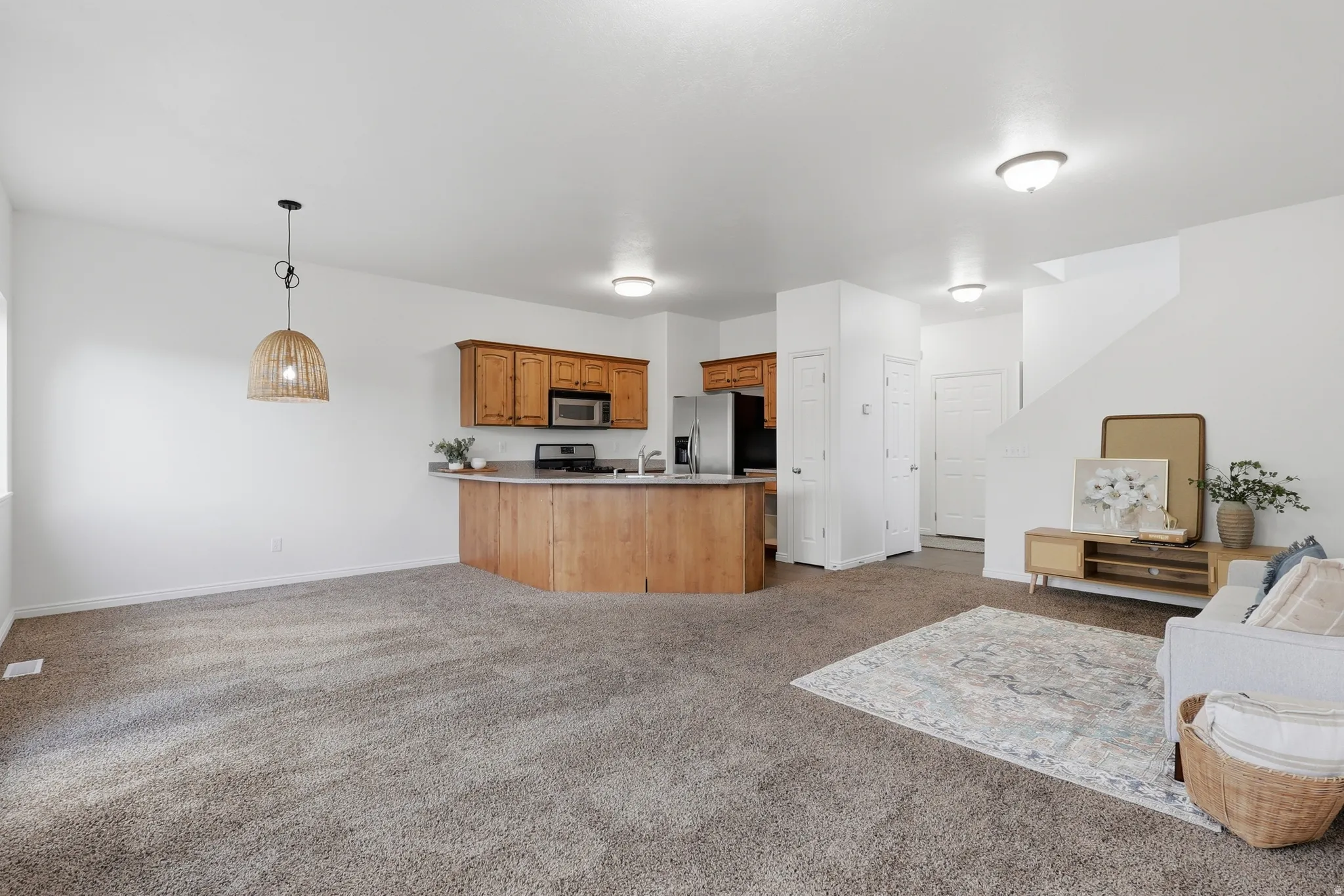 Kitchen with open floor plan, light carpet, a peninsula, and wood finish cabinetry