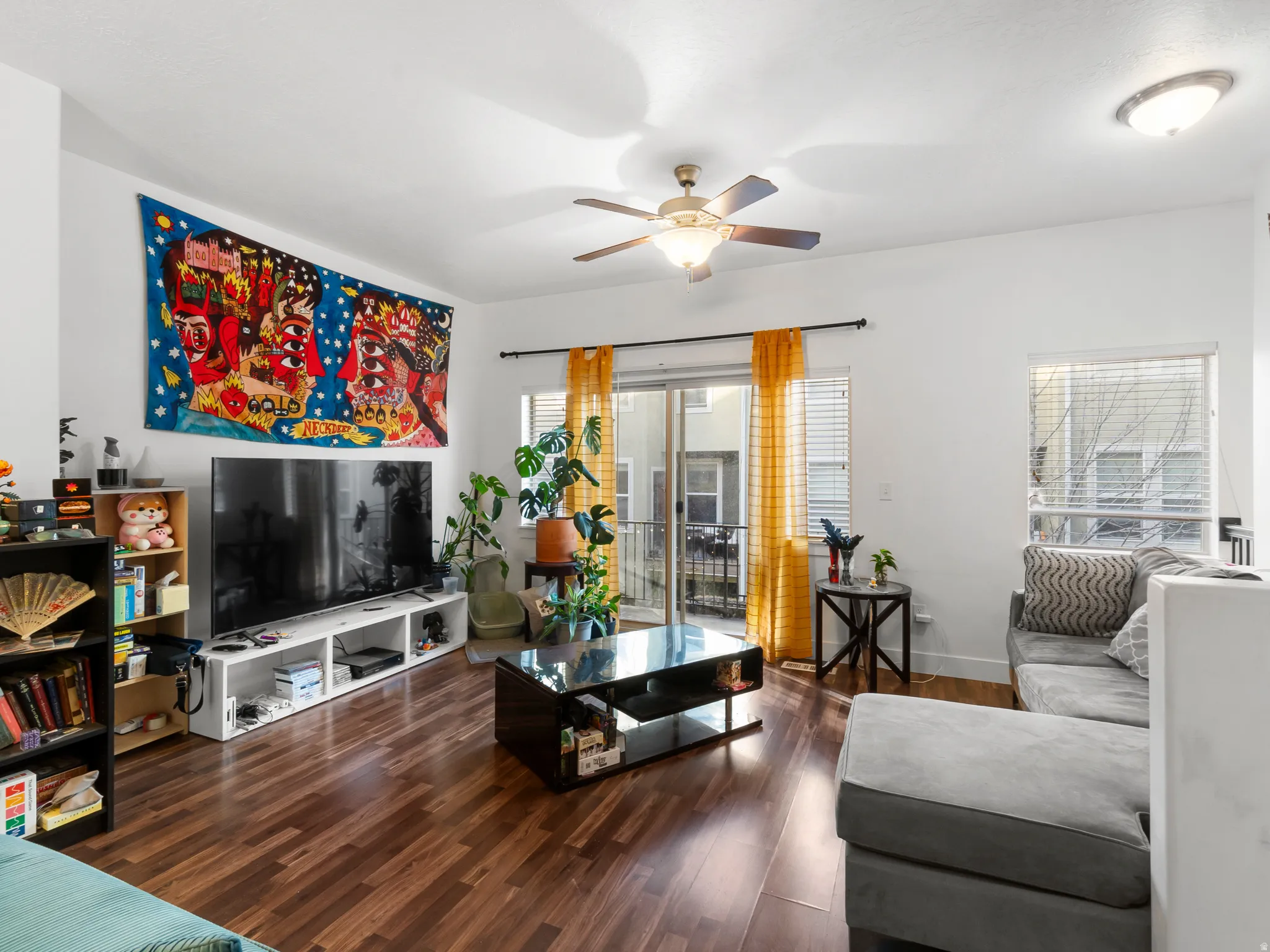 Living room with dark wood-type flooring and a ceiling fan