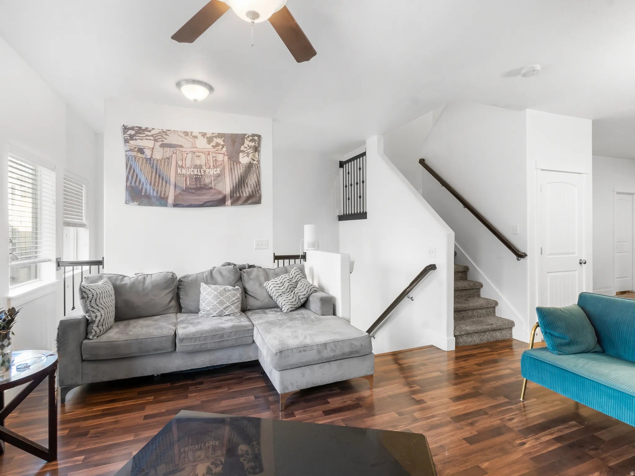 Living room featuring a ceiling fan and dark wood-type flooring