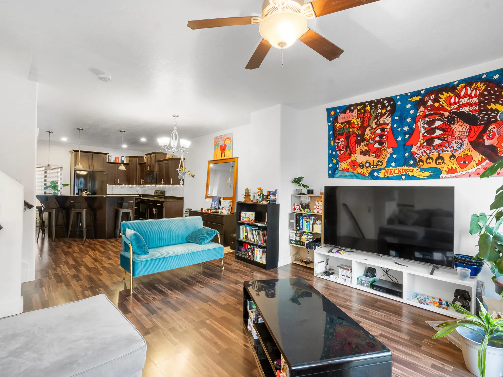 Living room with a chandelier, dark wood finished floors, and ceiling fan