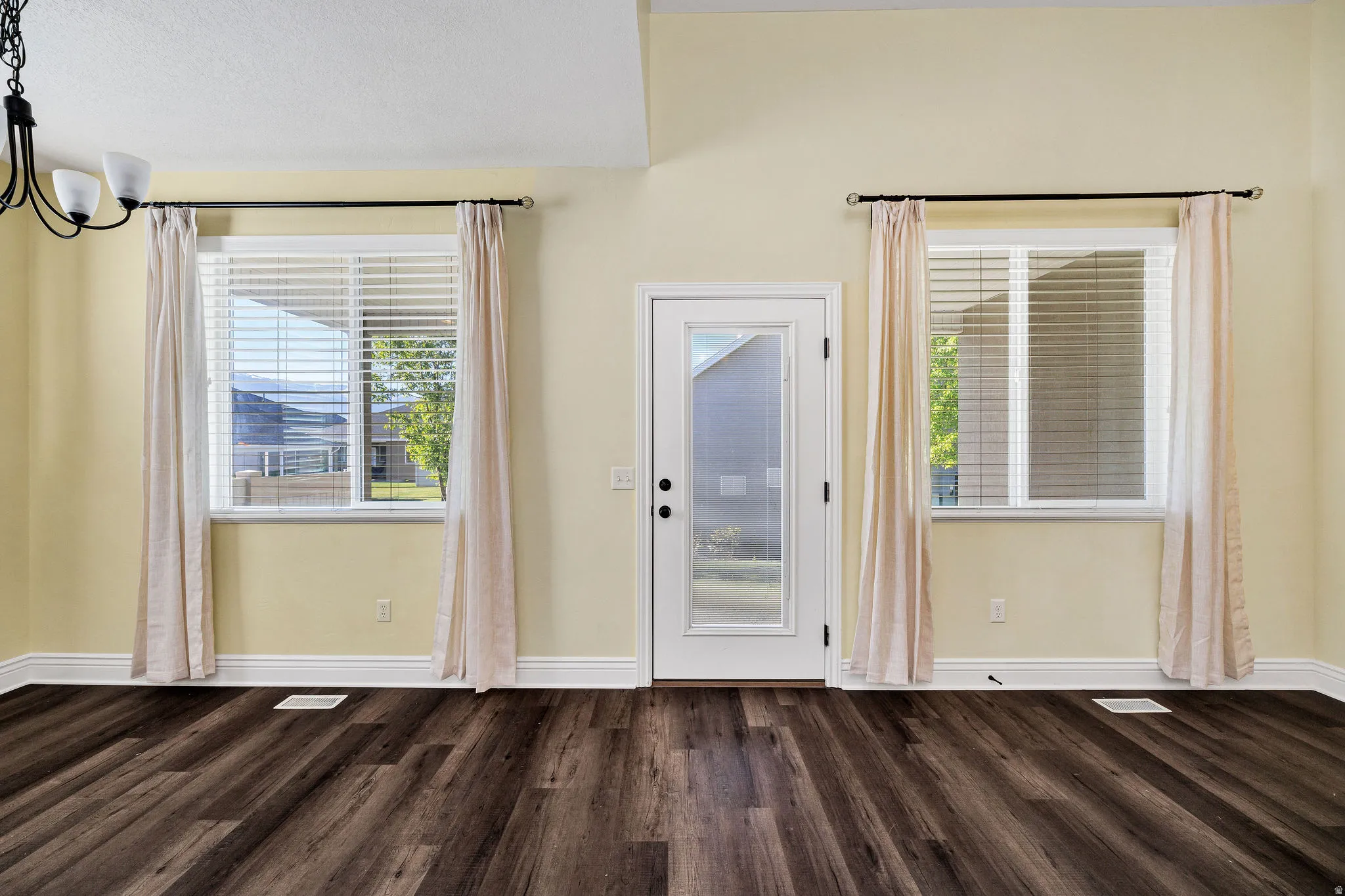 Doorway to back patio featuring wood finished floors and suspended lighting
