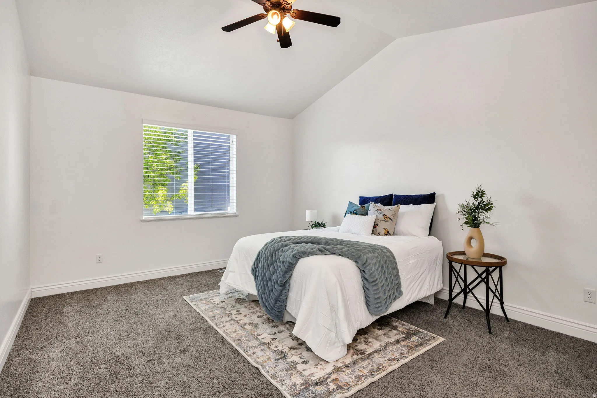 Primary Bedroom with vaulted ceiling, dark colored carpet, and ceiling fan