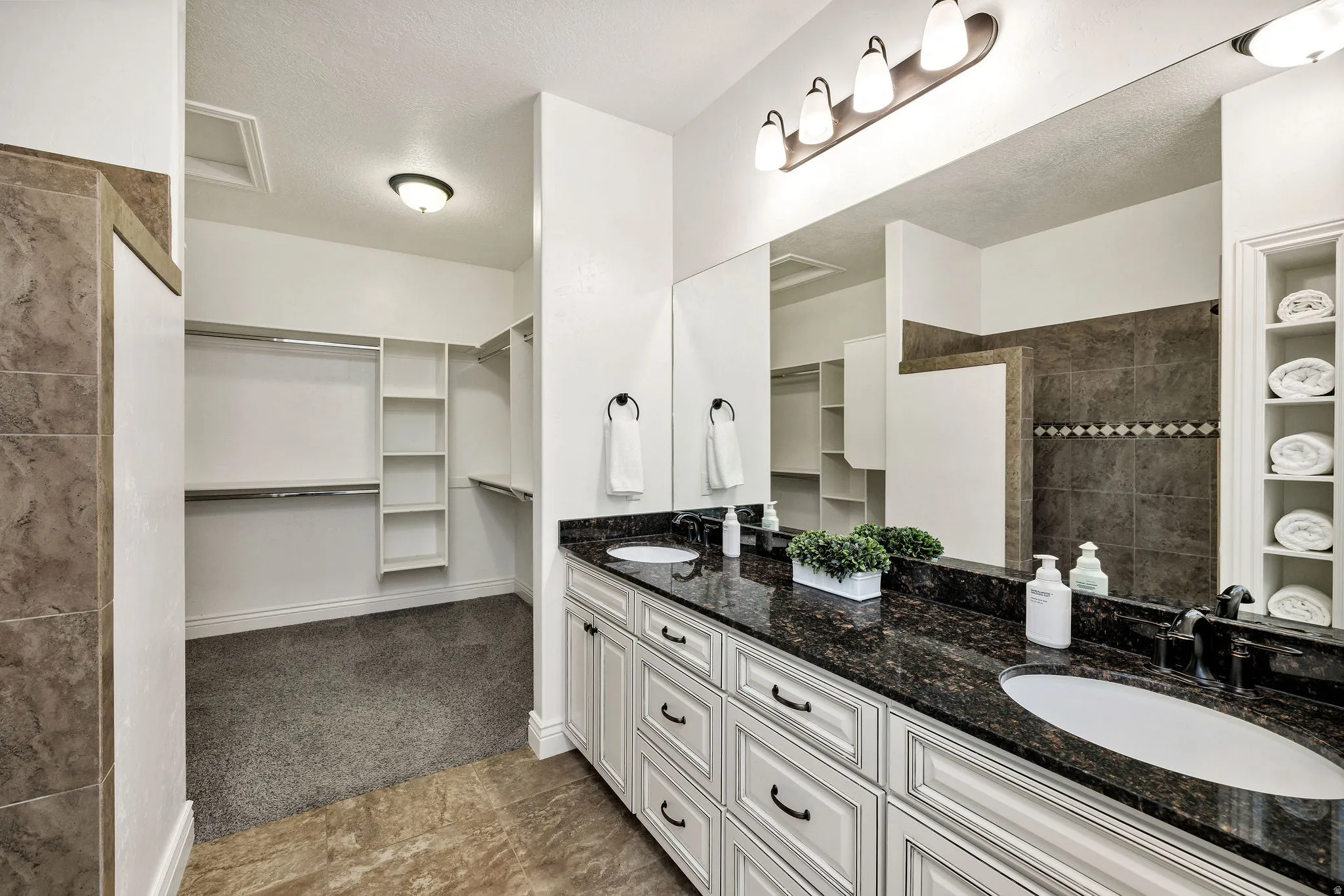 Ensuite bathroom featuring a spacious closet, double vanity, built in shelves