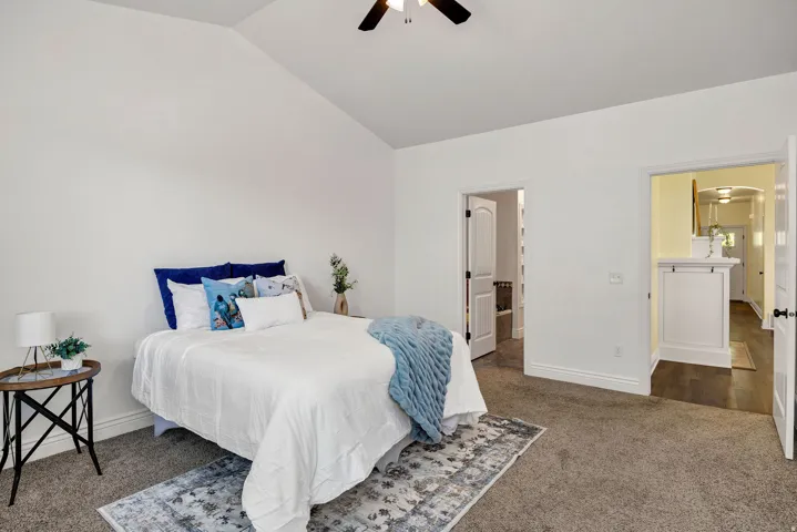 Bedroom featuring dark carpet, vaulted ceiling, and a ceiling fan