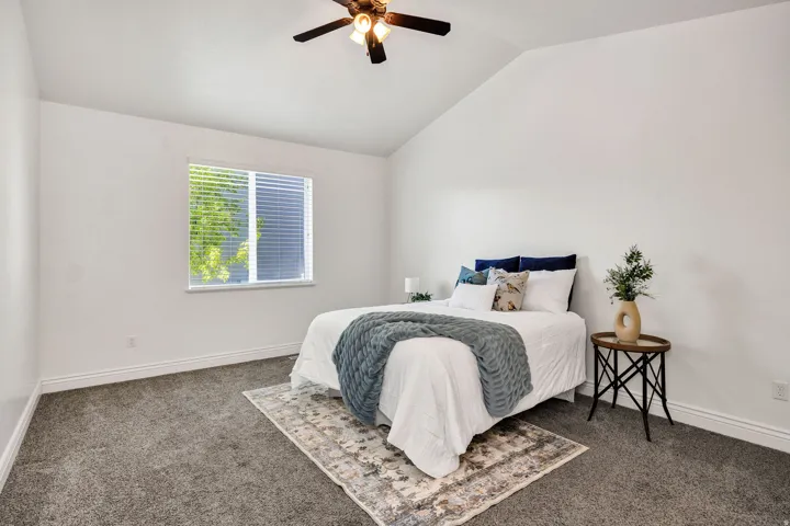 Primary Bedroom with vaulted ceiling, dark colored carpet, and ceiling fan