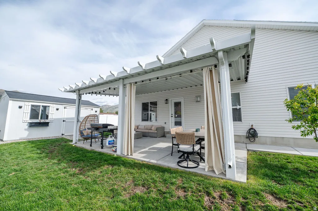 Back of house with a patio area, an outdoor structure, an outdoor living space, and a pergola