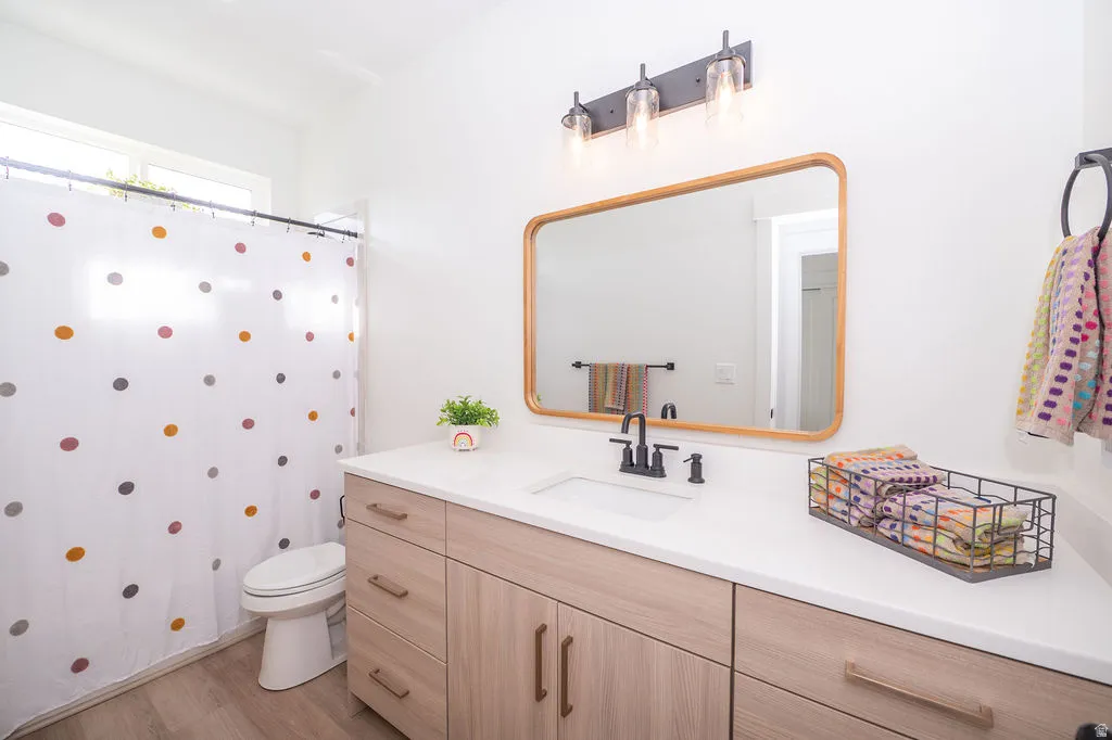 Full bath featuring vanity, a shower with shower curtain, and light wood-style floors