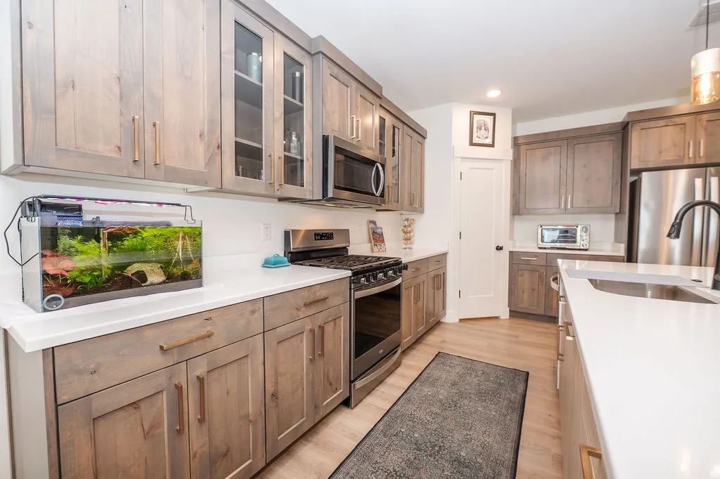 Kitchen featuring stainless steel appliances, glass fronted cabinets, light wood-type flooring, and pendant lighting
