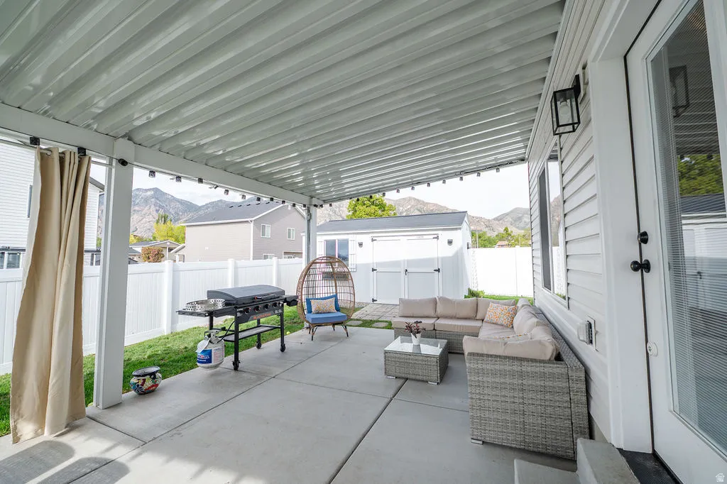 Fenced backyard with a mountain view, a patio, outdoor seating, area for grilling, and a storage shed