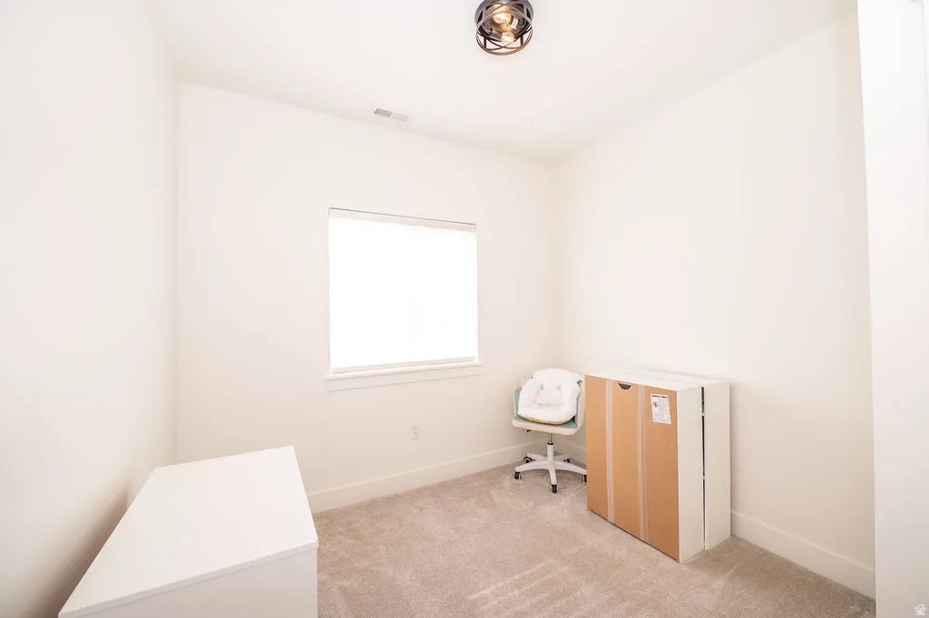Office space with light colored carpet and baseboards