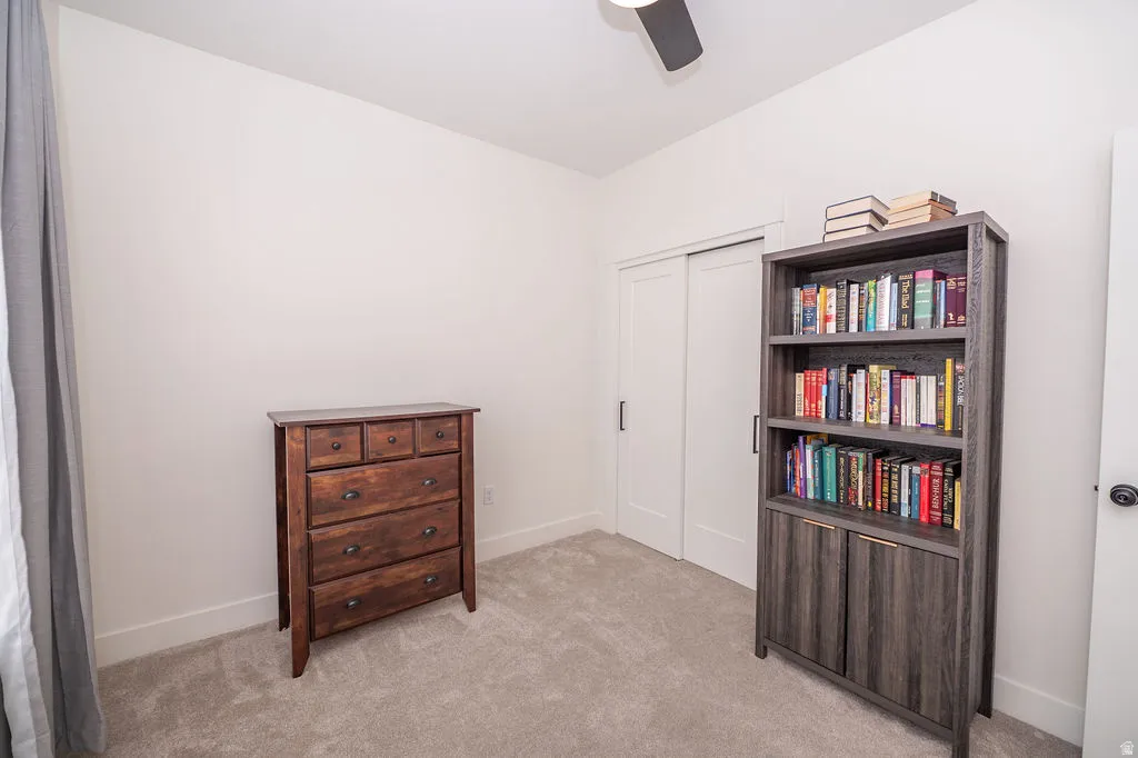 Bedroom with light colored carpet, ceiling fan, and a closet