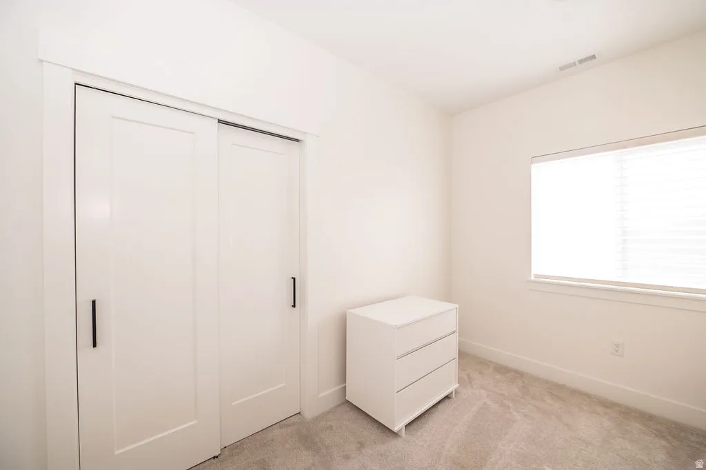 Unfurnished bedroom featuring light carpet and a closet