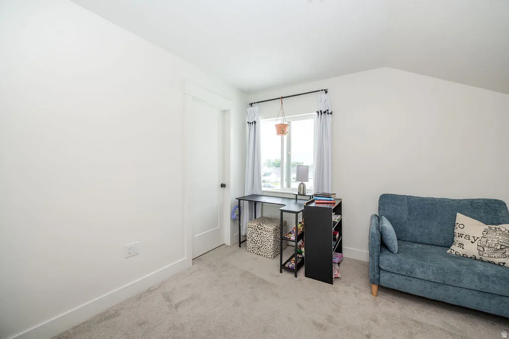 Home office with light carpet and lofted ceiling