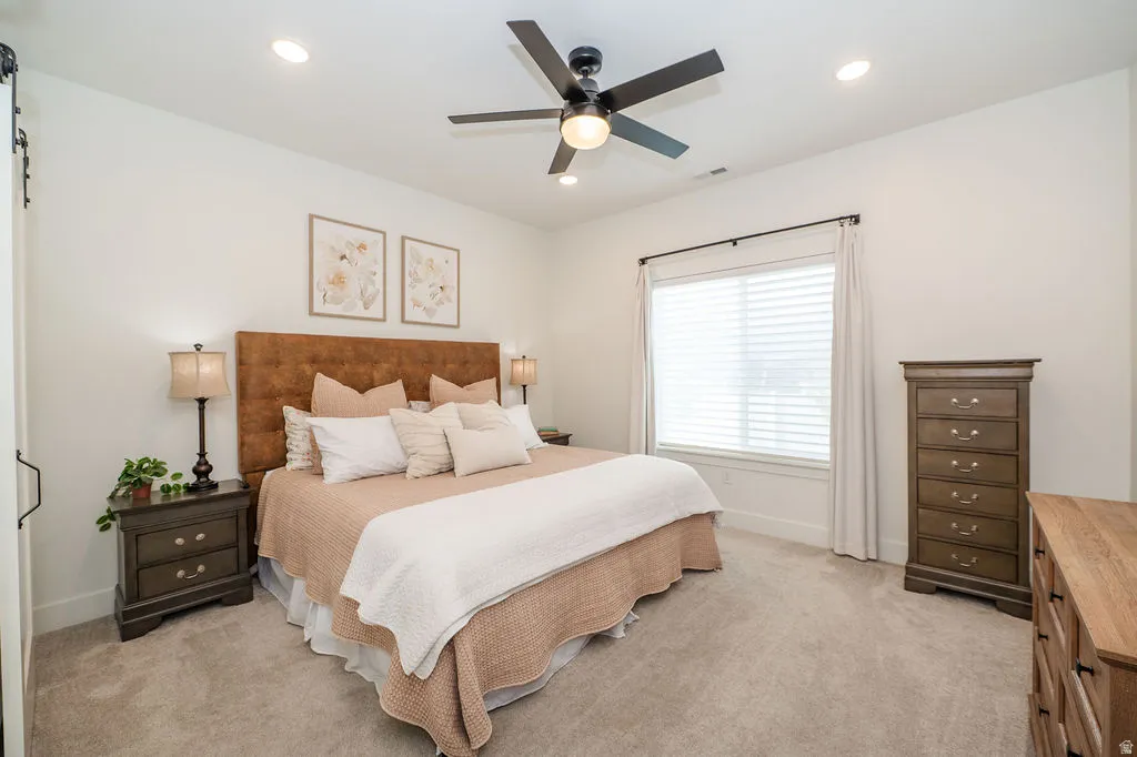 Bedroom with a ceiling fan, light carpet, and recessed lighting
