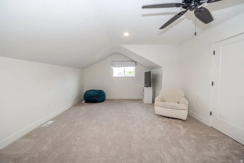 Unfurnished room featuring vaulted ceiling, light colored carpet, ceiling fan, and recessed lighting