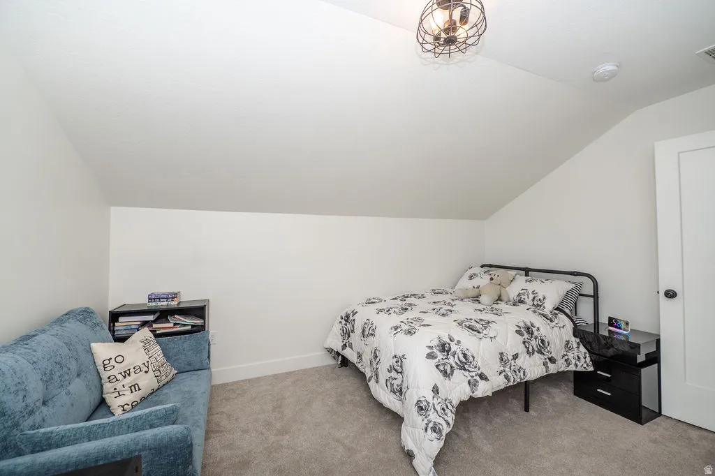 Carpeted bedroom featuring vaulted ceiling and baseboards
