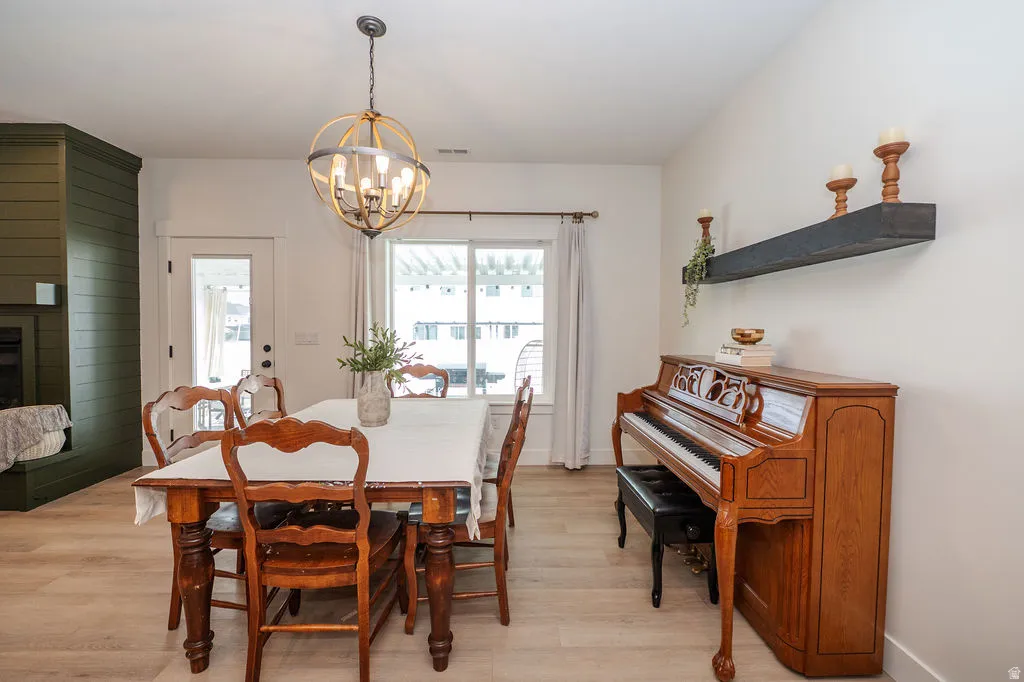 Dining area with a fireplace, light wood finished floors, and a chandelier