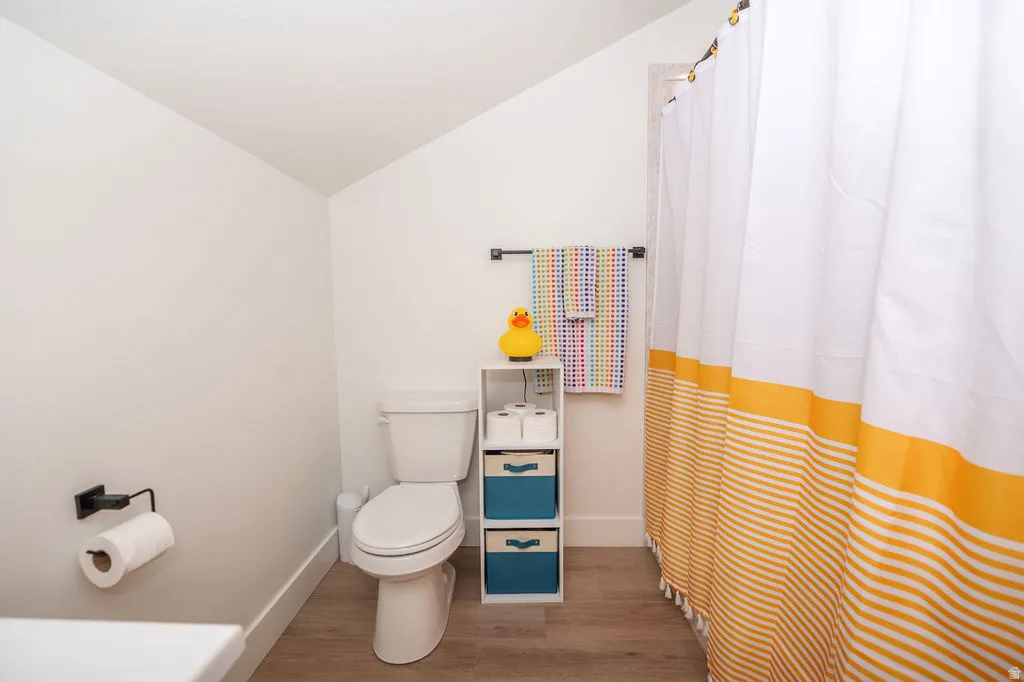 Bathroom with vaulted ceiling, a shower with curtain, and light wood finished floors