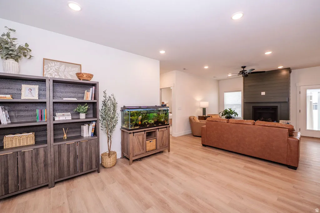 Living area featuring light wood-style flooring, recessed lighting, ceiling fan, and a fireplace