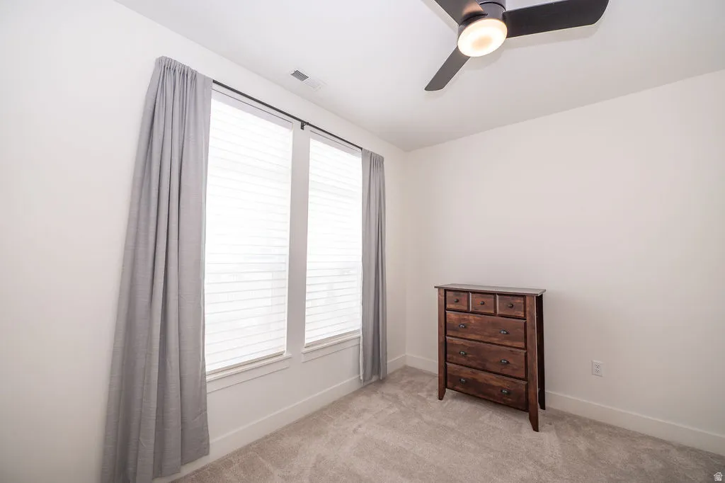 Bedroom with a ceiling fan and light carpet