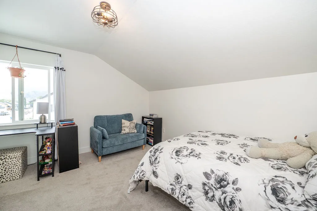 Bedroom featuring lofted ceiling and light carpet
