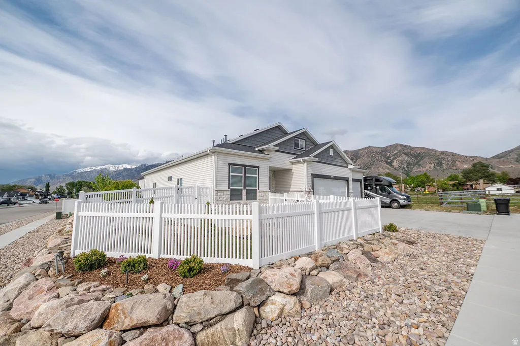 View of front facade with a fenced front yard, a mountain view, and driveway