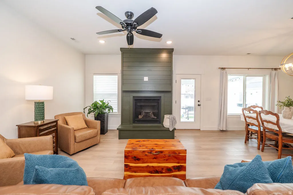 Living room featuring light wood finished floors, a ceiling fan, plenty of natural light, a large fireplace, and recessed lighting