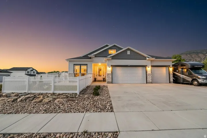 Craftsman house with a fenced front yard, a garage, stone siding, and concrete driveway