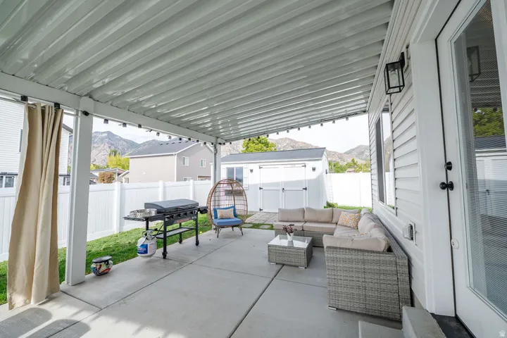 Fenced backyard with a mountain view, a patio, outdoor seating, area for grilling, and a storage shed