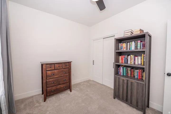 Bedroom with light colored carpet, ceiling fan, and a closet