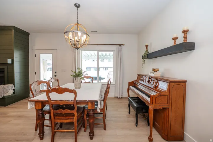 Dining area with a fireplace, light wood finished floors, and a chandelier