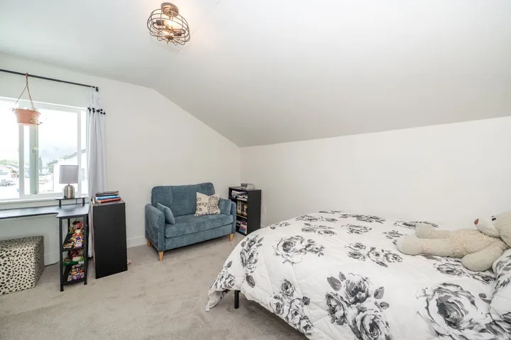 Bedroom featuring lofted ceiling and light carpet