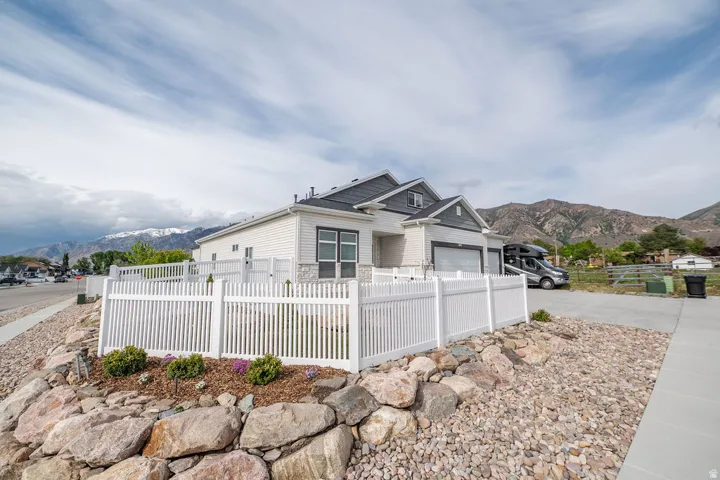 View of front facade with a fenced front yard, a mountain view, and driveway