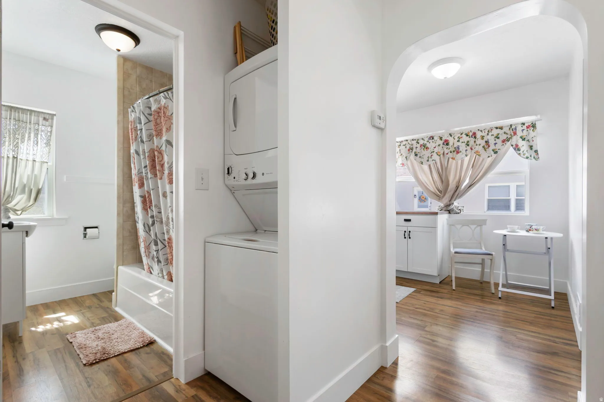 Laundry area with stacked washer / dryer, dark wood-type flooring, and healthy amount of natural light