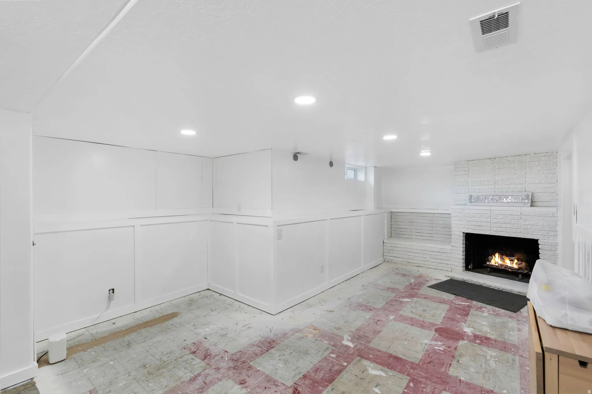 Basement with a decorative wall, a brick fireplace, wainscoting, and recessed lighting