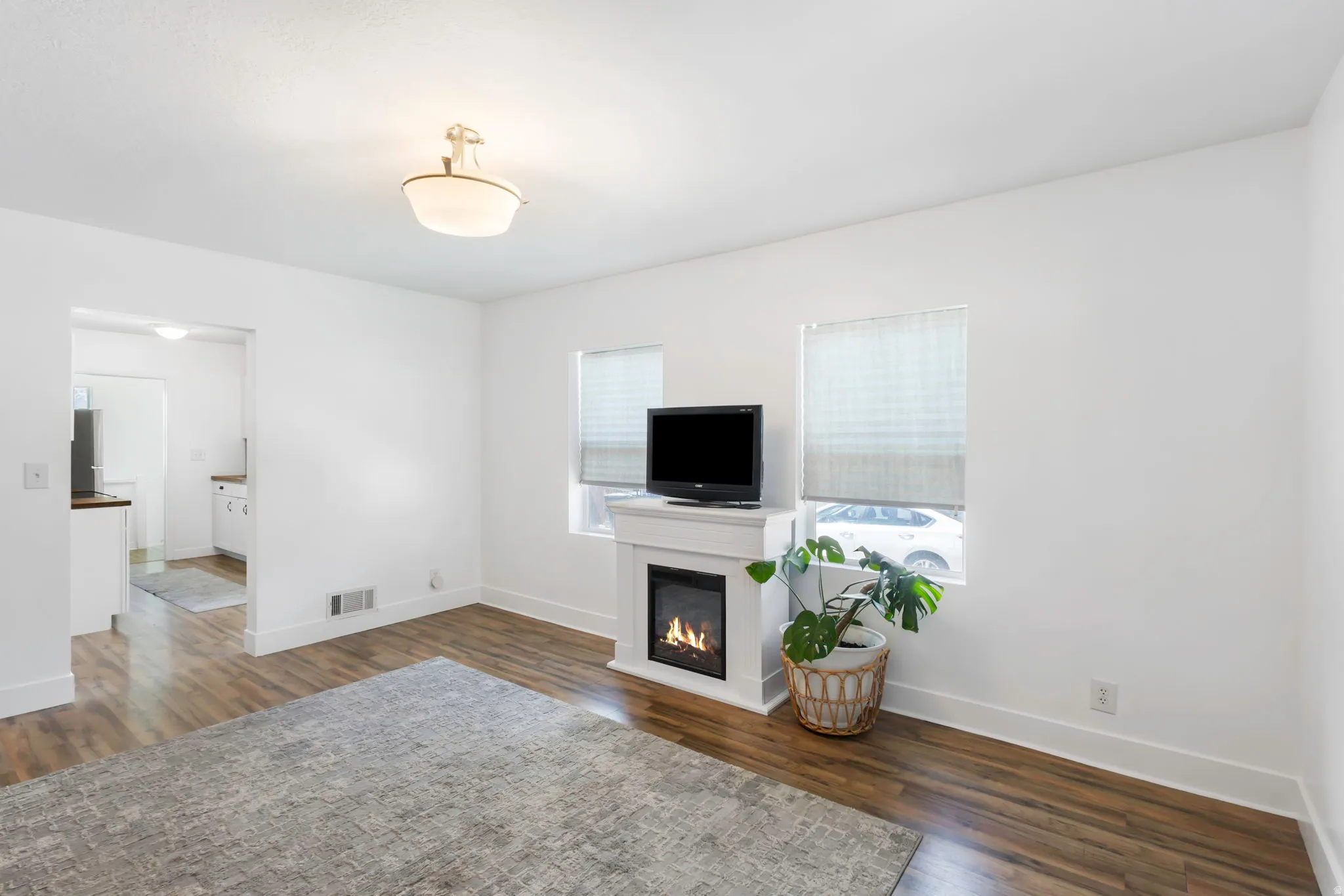 Unfurnished living room with dark wood finished floors and a glass covered fireplace