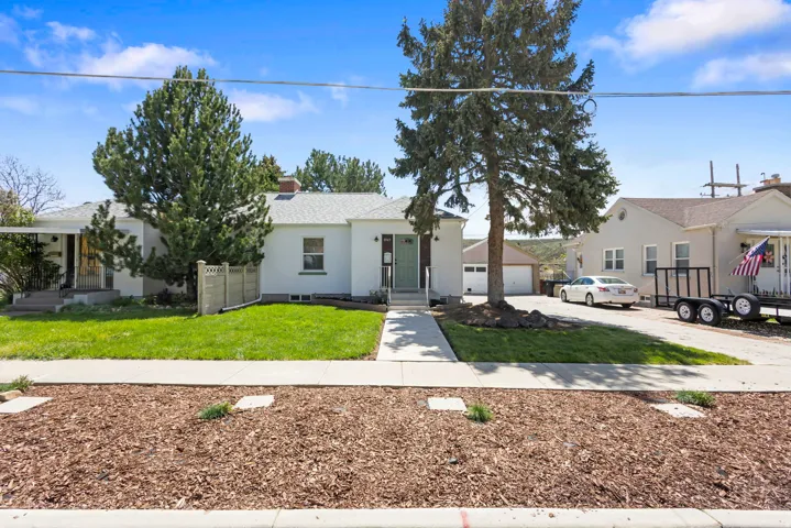 Bungalow-style home featuring a chimney, a front yard, and driveway